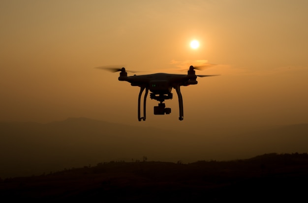 Hommelsilhouet die in zonsonderganglandschap vliegen met digitale camera bij zonsondergang klaar te vliegen.