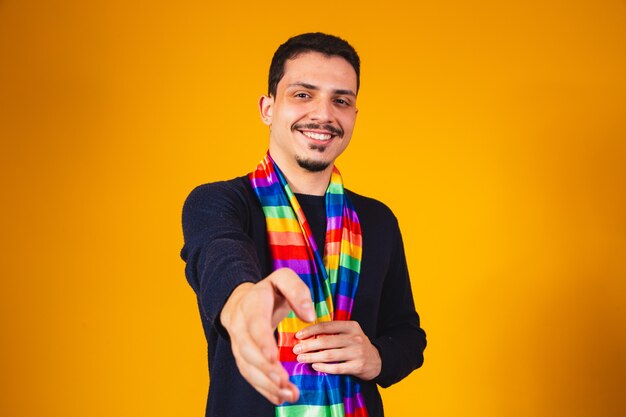 Homoaffective boy with lgbt flag around his neck stretches out his hand for a handshake