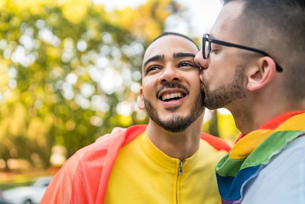 Homopaar die en hun liefde met regenboogvlag omhelzen tonen.