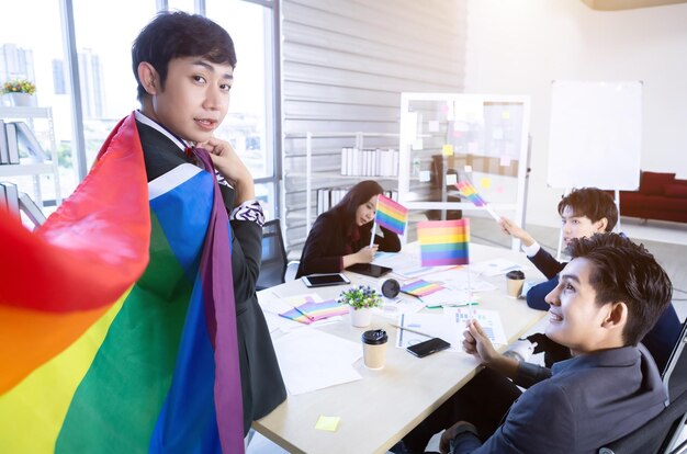 Homoseksuele Aziatische zakenman met LGBT-vlag en succesvolle gelukkige werknemers met werknemers in het bedrijf Groep Aziatische zakenmensen en ondersteuning in de vergaderruimte op kantoor