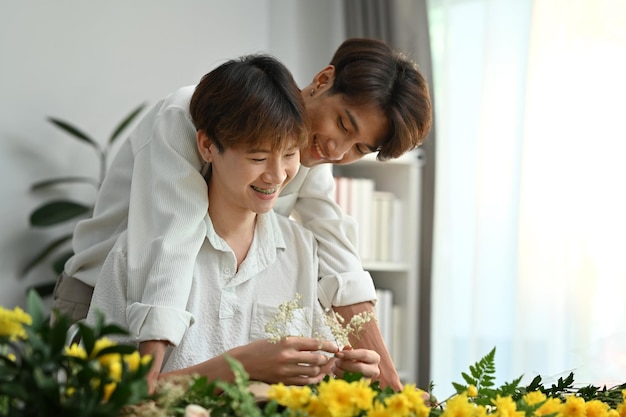 Homoseksuele LHBT en relaties Blij mannelijk homopaar dat samen tijd doorbrengt en geniet van het regelen van bloemen in een gezellig huis