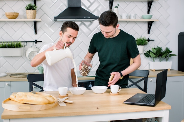 Homosexual couple, gay people, same sex marriage between Caucasian men. Male partners having breakfast and cooking in kitchen at home