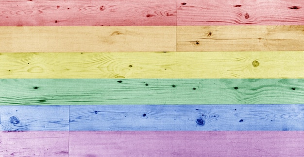 Omosessualità, minoranze sessuali, design e concetto di sfondo - motivo a bandiera arcobaleno pallido gay pride su superficie di legno