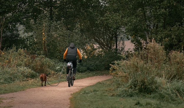 Hond en fiets Achteraanzicht van een man die op een fiets rijdt terwijl zijn hond naast hem rent