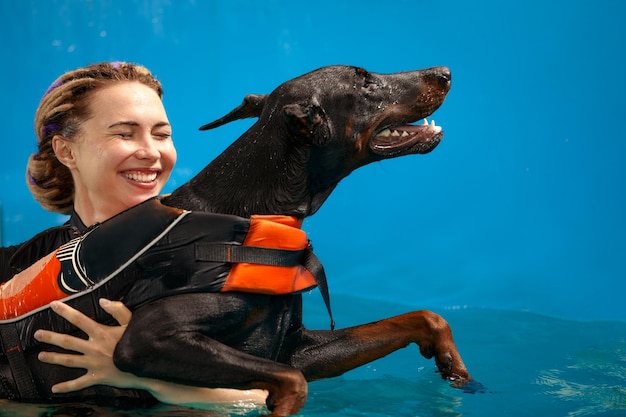 Hond in reddingsvest zwemmen in het zwembad met coach huisdieren rehabilitatie herstel training