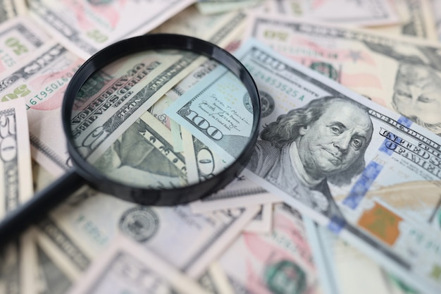 Honderd-dollarbiljetten en vergrootglas liggen op tafel op zoek naar een nieuw investeringsconcept