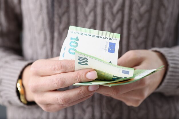 Honderd eurobankbiljetten in vrouwelijke handen besparingen in europees landenconcept
