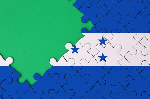 Photo honduras flag  is depicted on a completed jigsaw puzzle with free green copy space on the left side