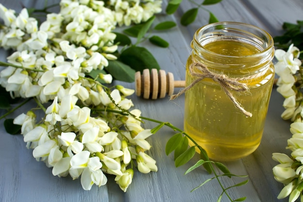 Honey and acacia flowers on the grey wooden