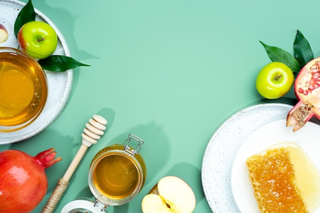 Honey apple and pomegranate on a mintgreen background Concept Jewish New Year Happy holiday Rosh Hashanah Creative layout of traditional symbols View from above Flat lay Copy space Shana Tova