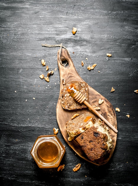 Sfondo di miele. pane alla frutta con miele naturale e noci. sulla tavola rustica nera.