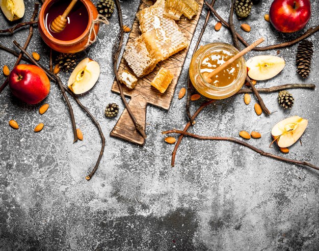 Honey background. Honey with apples and nuts on rustic table.