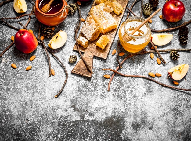 Honey background. Honey with apples and nuts on rustic table.