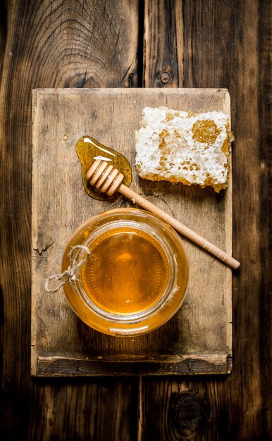 Honey background. The jar of honey, honey comb and spoon on a wooden Board. On wooden background.