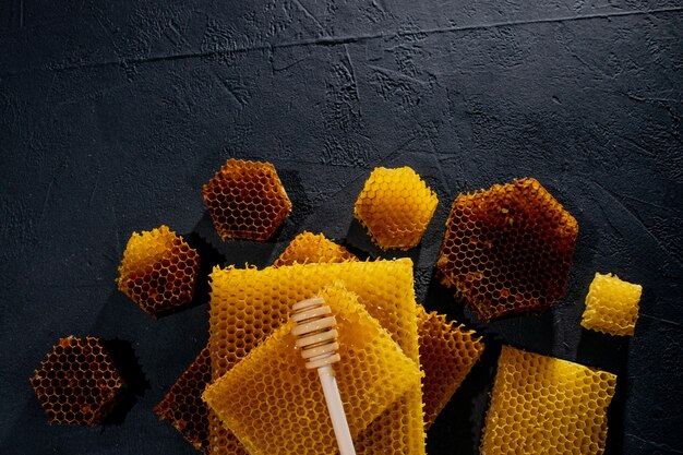 Honey background. Natural honey comb and a wooden spoon . On black rustic table.