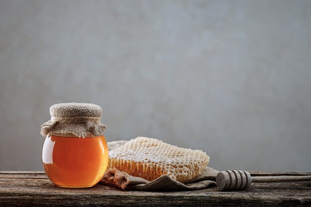 Honey background. Sweet honey in the comb, glass jar. On wooden background