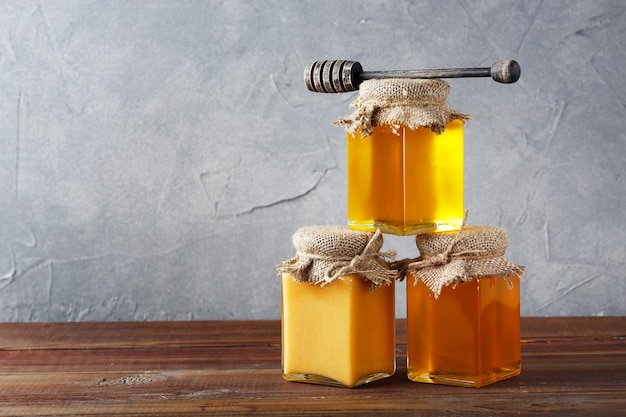 蜂蜜の背景。甘い蜂蜜、ガラスの瓶。木製の背景に。