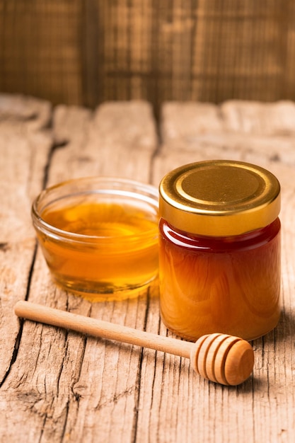 Honey in bowl dipper on an aged wooden background