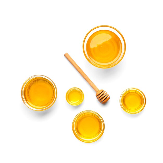 Honey in bowls and dipper on a white background top view