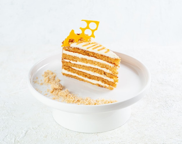 Honey cake based on buckwheat and lime honey with cream. On a white plate Light background.