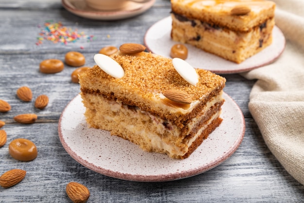 Honey cake with milk cream, caramel, almonds and a cup of coffee