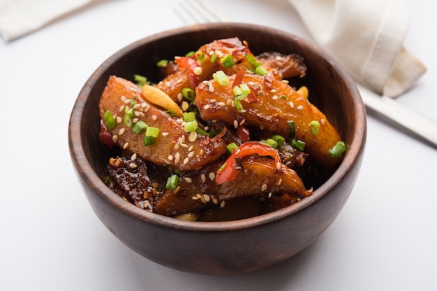 Honey Chilli Potato Wedges, popular Indian-Chinese starter recipe, garnished with sesame and onion. selective focus