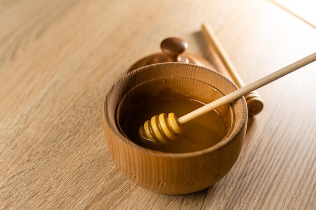 honey in a deep wooden bowl, rustic wooden plate. The wooden spoon drips slowly.