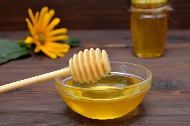 Honey dipper and honey in a glass bowl closeup