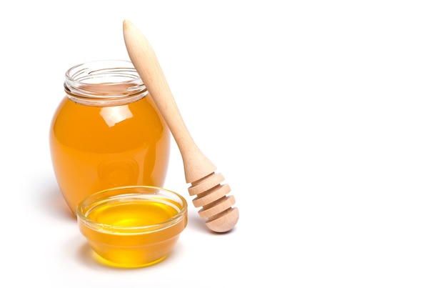 Honey dipper and honey in jar on white background