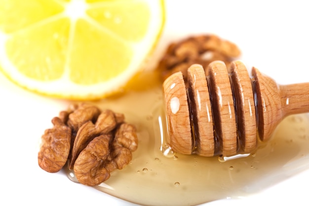 Honey dipper, walnut and lemon on a white background.