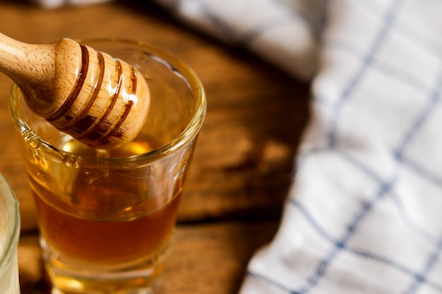 Honey dripping from a glass on wooden table