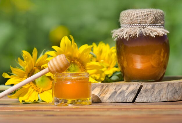 Honey dripping from honey dipper Different kinds of honey on wooden  background Healthy organic honey