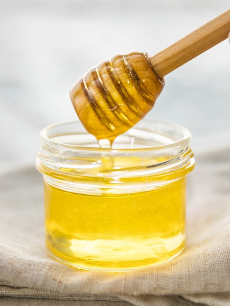 Honey dripping from honey dipper in the glass jar