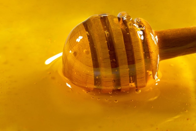 Мед капает из медового ковша в деревянную миску Крупным планом Здоровый органический