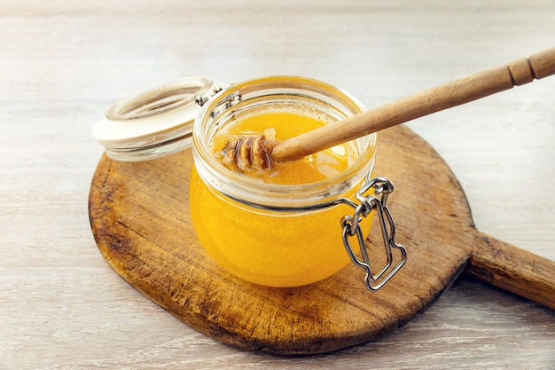 Honey dripping from a wooden dipper on old cutting board