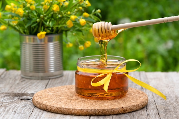 Honey drips from the spoon into the jar