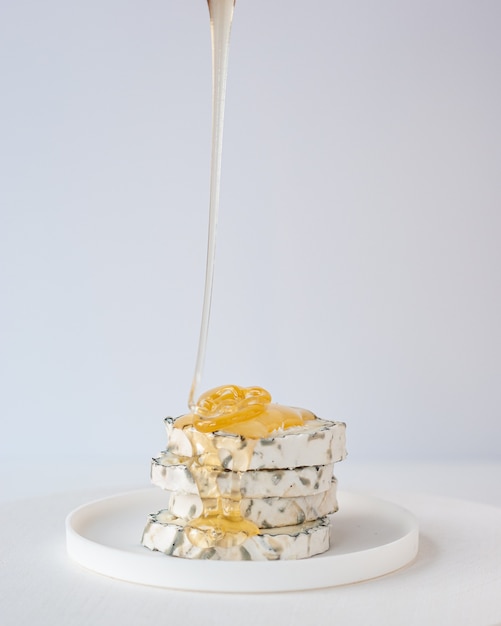 성형 염소 치즈 조각 위에 꿀 방울