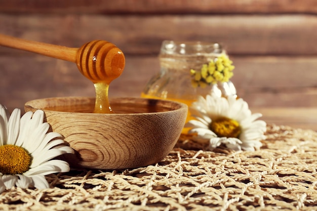 Honey and flowers on wicker mat