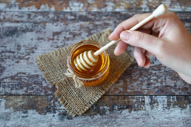 Honey flows from the honey dipper. Jar of honey and a dipper for honey. Selective focus.  Healthy sweets.