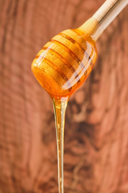 Honey flows on a wooden honey stick vertical shot closeup and selective focus on honey Natural products from farms in Turkey