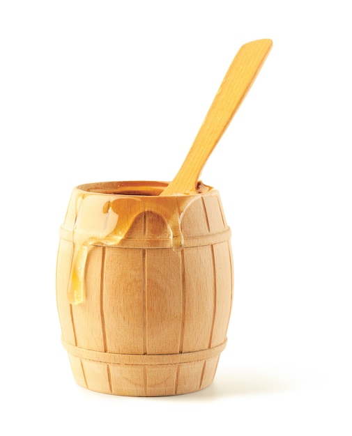 Honey flows on a wooden keg. The keg is opened and in it a spoon