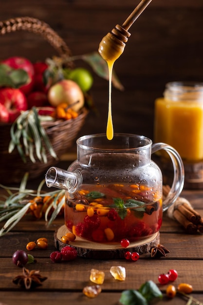 Honey from a spoon flows into a teapot with berries