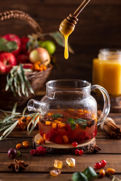 Honey from a spoon flows into a teapot with berries