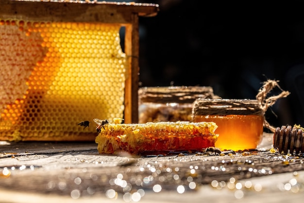 Foto miele in ciotola di vetro, mestolo di miele in legno e favi con miele sulla tavola di legno