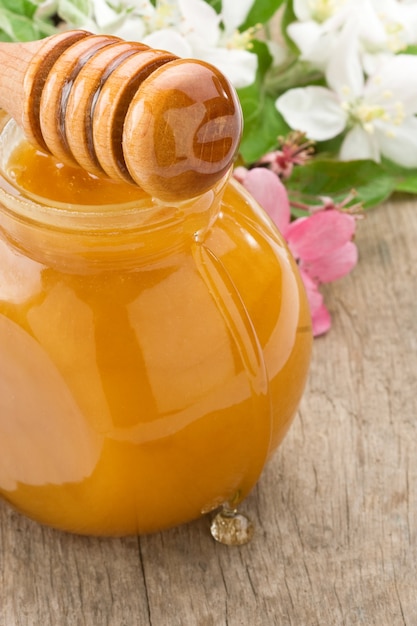 Honey in glass jar and stick on wood