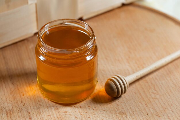 Honey in a glass jar with a wooden honey dipper on a wooden table Healthy organic honey