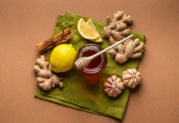 Honey glass pot, ginger, garlic, lemon, cinnamon top view to boost immune system. Natural food ingredients for immunity stimulation and viruses protection. Healthy food against seasonal flu and cold