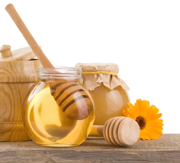 Honey in glass and wood pot isolated on white