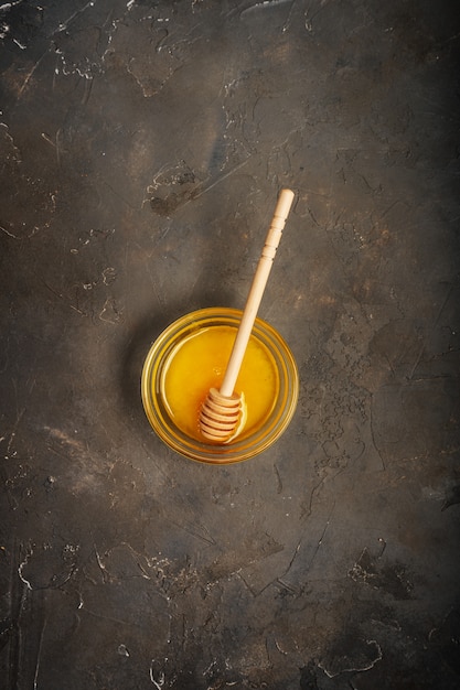 Honey and Honey spoon on dark background with copy space.  Taken from above.