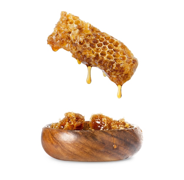 Photo honey in a honeycomb dripping into a wooden plate